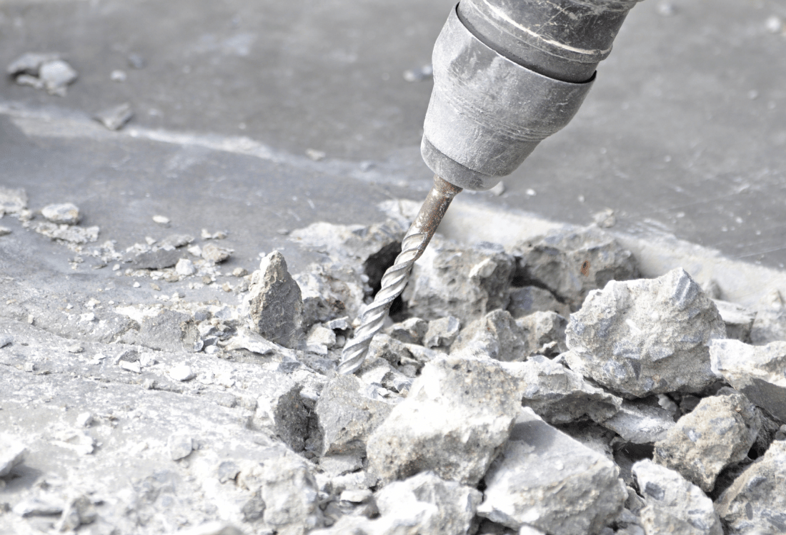 Concrete drilling in progress, with a cloud of dust surrounding the drill, illustrating the potential health hazards of uncontrolled dust.