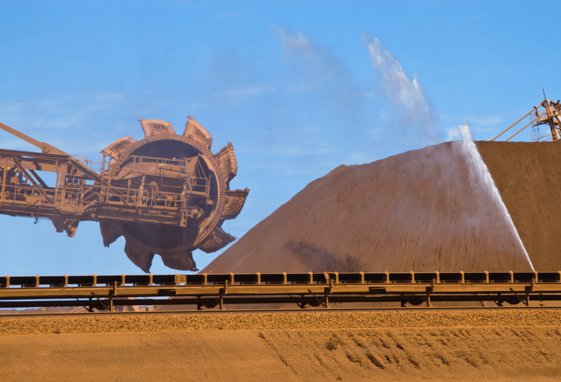 Stockpile of iron ore at a mining site with Stockpile dust suppression technique being used to control stockpile dust.