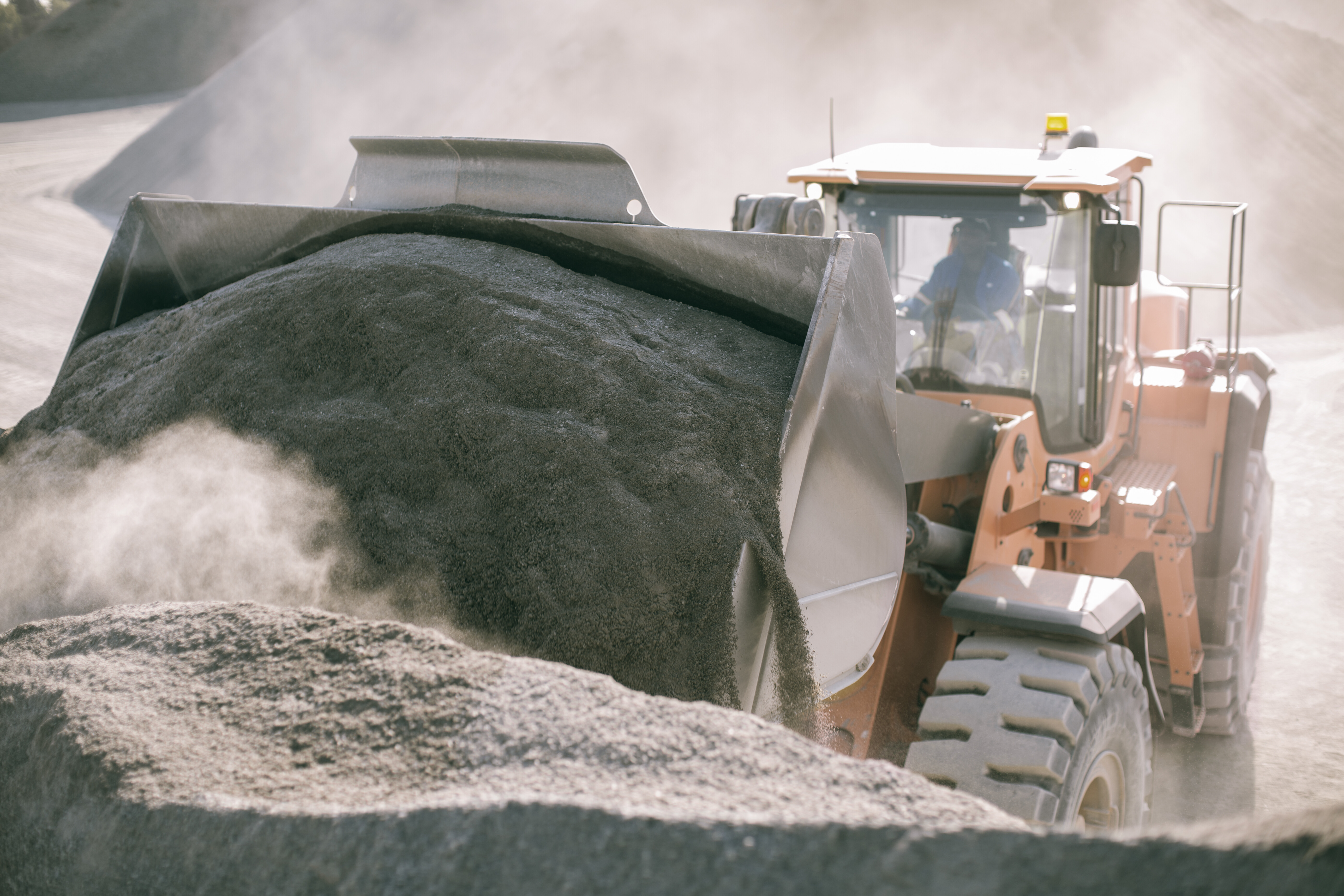 Front loader moving aggregate during stockpile dust control operations at a quarry.